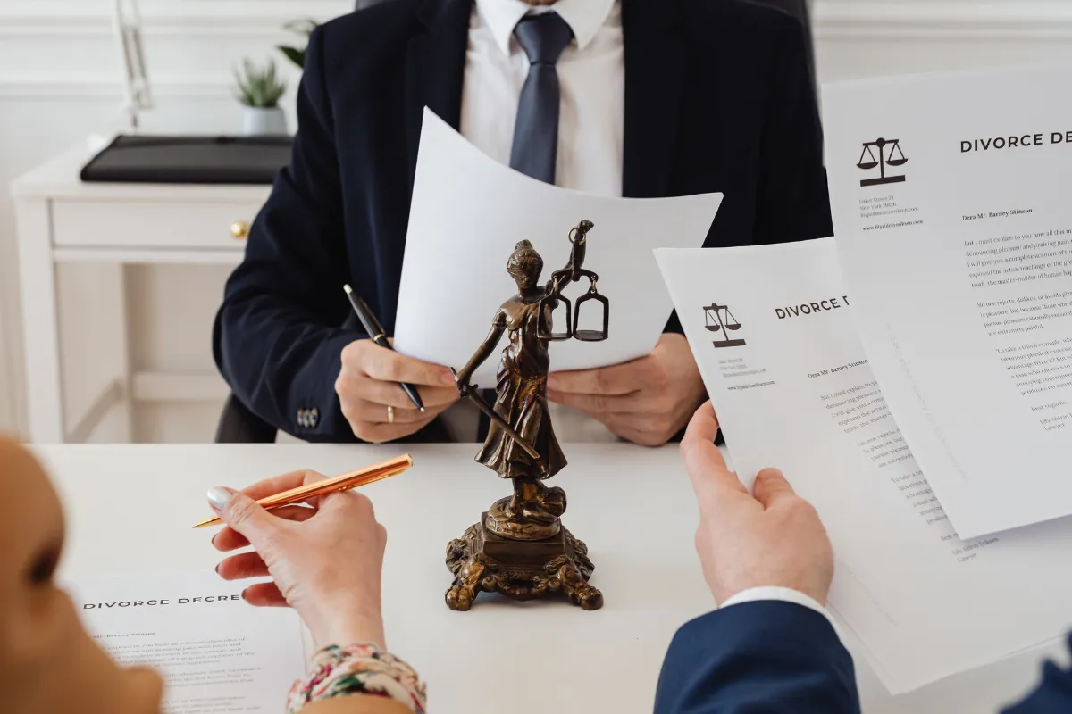 Divorce advocates in Bangalore reviewing divorce decrees with clients, Lady Justice statue on desk.
